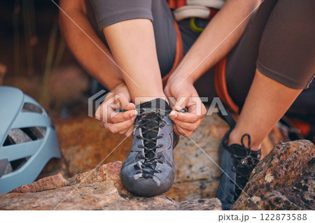 Woman tying her hiking shoes in nature preparing for a rock climbing or trekking exercise. Fitness, footwear and healthy girl doing outdoor sports activity or adventure on a mountain for wellness. 122873588