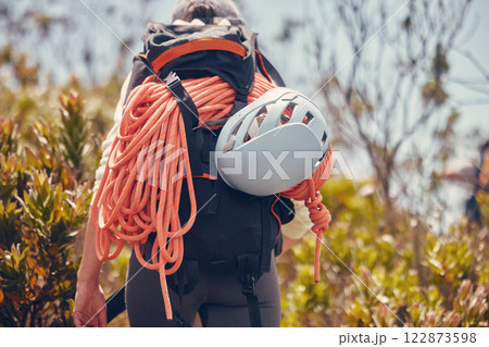 Sports, mountain and climbing with a person hiking and carrying equipment, rope and a helmet outdoor in nature. Adventure, sport and fitness with an adult on a climb, journey or hike in the forest 122873598