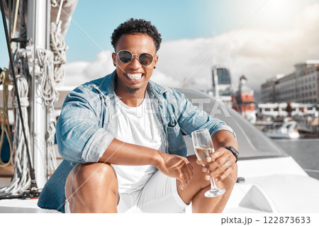 Happy, sea and man on a luxury yacht or catamaran enjoying a glass of champagne on a summer holiday alone. Lifestyle, smile and young person in sunglasses drinking wine on cruise boat to relax at sea 122873633