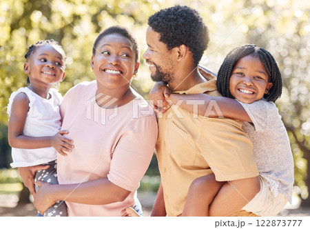 Black family, nature and parents carrying children, bonding and spending free time on a sunny day. Support, love and happy caring man and woman on a walk at a park with their cute girls outside. Black family, nature and parents carrying children, bonding and spending free time on a sunny day. Support, love and happy caring man and woman on a walk at a park with their cute girls outside. 122873777