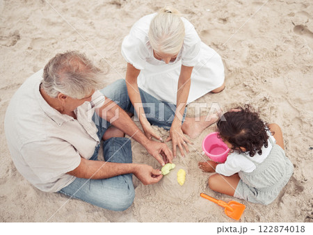 Family, beach and play with grandparents and child building sand castle together for vacation, fun and relax. Summer, happy and retirement couple with young girl playing by the sea for holiday break 122874018
