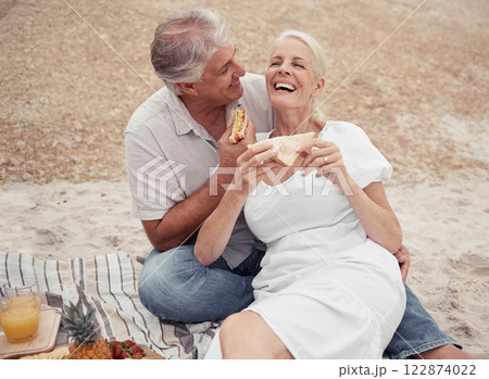 Love and healthy senior couple on picnic at a beach eating sandwich with funny conversation for wellness, healthcare or retirement. Outdoor elderly woman and man with cheese bread together on ground Love and healthy senior couple on picnic at a beach eating sandwich with funny conversation for wellness, healthcare or retirement. Outdoor elderly woman and man with cheese bread together on ground 122874022