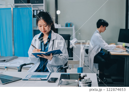 Positive doctor working on laptop in medical office, portrait. 122874653