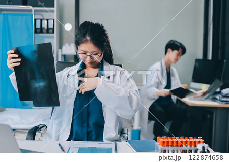 Positive doctor working on laptop in medical office, portrait. 122874658