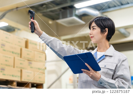 倉庫でハンディターミナルとタブレットPCを持って作業する女性従業員 122875187