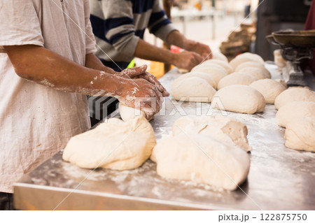 Male hands knead yeast dough for baking bread 122875750