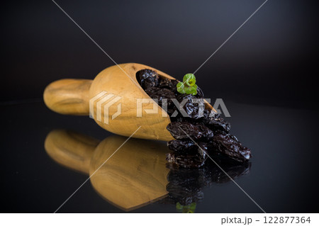 Prunes in a wooden spoon on a dark background Prunes in a wooden spoon on a dark background 122877364