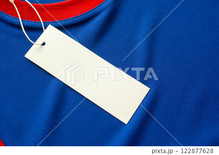 Blank white clothes tag label on blue fabric texture background 122877628