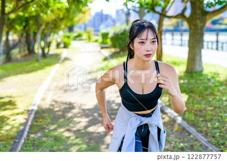 木漏れ日の道をジョギングするかっこいい女性　走る　ダイエット　エクササイズ　運動　 122877757