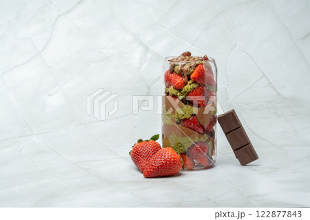 Trend Dubai chocolate strawberry cup with kunafa, pistachio paste, tahini, milk chocolate and fresh strawberries. Decorated with strawberries and chocolate bar piece. Copy space for text. 122877843