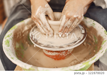 Mutual creative work. Young beautiful couple in casual clothes and aprons. People creating a bowl on a pottery wheel in a clay studio. 122878020