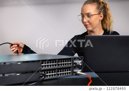IT technician professional configuring network switch and managing network cables and hardware in a data center environment IT technician professional configuring network switch and managing network cables and hardware in a data center environment 122878493
