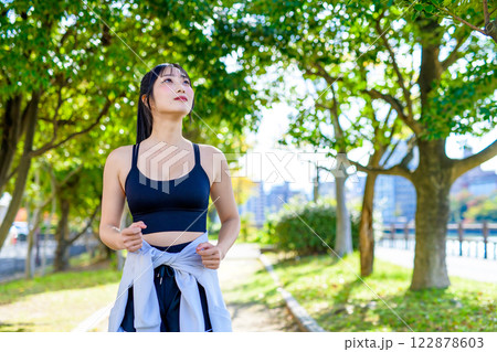 木漏れ日の道をジョギングするかっこいい女性　歩く　ダイエット　エクササイズ　運動　 122878603