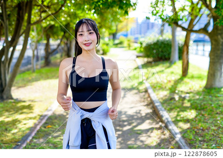木漏れ日の道をジョギングするかっこいい女性　歩く　ダイエット　エクササイズ　運動　 122878605
