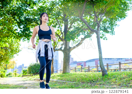 木漏れ日の道をジョギングするかっこいい女性　歩く　ダイエット　エクササイズ　運動　朝カラー 122879141