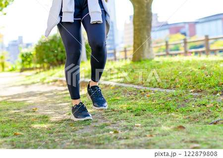 木漏れ日の道をジョギングするかっこいい女性　歩く　ダイエット　エクササイズ　運動　トリミングアップ 122879808