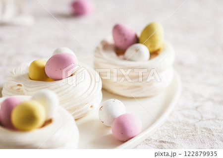 Easter meringue nests with colorful sweet eggs on plate. Easter dessert closeup. Easter meringue nests with colorful sweet eggs on plate. Easter dessert closeup. 122879935