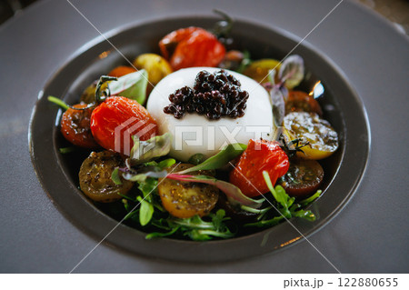 Indulge in Gourmet Burrata paired exquisitely with colorful Heirloom Tomatoes and a touch of Caviar 122880655