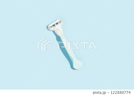 Minimalist elegance: Razor in sharp relief against a bold blue canvas with dramatic shadows Minimalist elegance: Razor in sharp relief against a bold blue canvas with dramatic shadows 122880774
