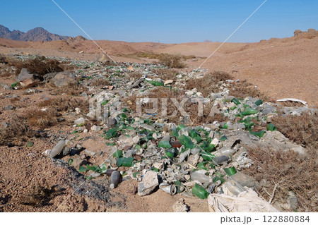 Broken bottles glass lies in desert, abuse of environment 122880884