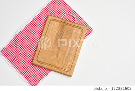 Empty wooden cutting board and red towel on white background. Copy space 122881602