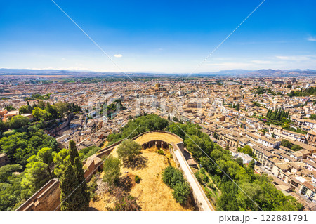 Granada town in Spain from the Alhambra complex. Panoramic view of a city from an elevated vantage point, showcasing a historic district with its unique architecture and surrounding landscape. 122881791