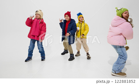 Group of children, wearing colorful winter jackets and hats, standing ready with snowballs, smiling and enjoying playful winter fun against white studio background. Group of children, wearing colorful winter jackets and hats, standing ready with snowballs, smiling and enjoying playful winter fun against white studio background. 122881852