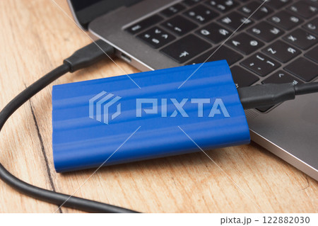 External hard drive connected to a laptop on a wooden desk. 122882030