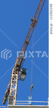 Operator Cabin And Long Boom Of High Rise Construction Crane On Blue Sky Background Vertical Stock Photo 122882286