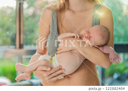 A mother lovingly embraces her newborn baby, holding them close to her chest. A tender moment of warmth, security, and deep maternal love, symbolizing bonding, comfort, and the unbreakable connection A mother lovingly embraces her newborn baby, holding them close to her chest. A tender moment of warmth, security, and deep maternal love, symbolizing bonding, comfort, and the unbreakable connection 122882404