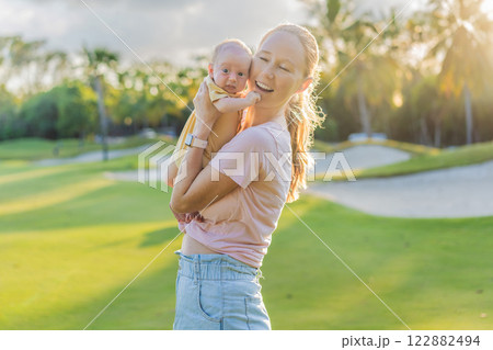 Young mother enjoying a peaceful walk in the park with her one-month-old baby. Motherhood, bonding, and outdoor family time concept 122882494