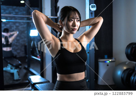 ジムで体を鍛える髪を結ぶかっこいい女性　パワーラック　ベンチプレス　筋トレ女子　トリミングアップ 122883799