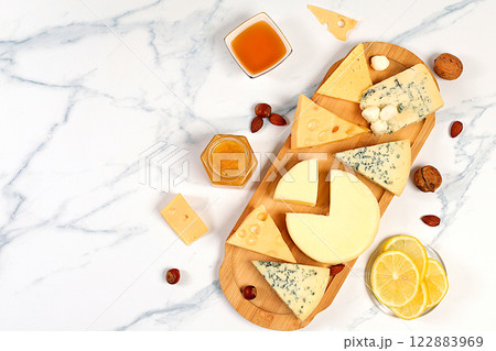 Assortment of different types of cheese, blue cheese, gorgonzola, roquefort, parmesan, mozzarella, maasdam with honey and nuts, healthy and natural food selection, cafe and menu advertising card 122883969
