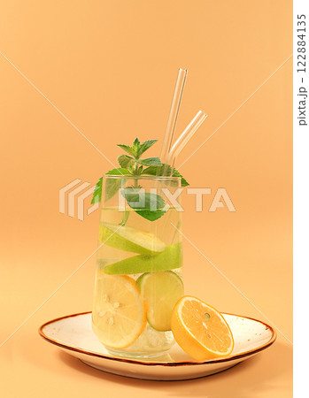 Detox water with lemon, cucumber, lime and mint flavors on a light background. A refreshing summer homemade lemonade cocktail. Fruit juice and ingredients, weight loss concept, healthy and natural 122884135