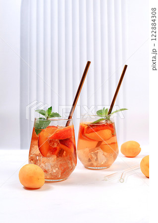 Ice peach tea or cocktail with mint and apricots, a recipe for a refreshing summer drink. Two glasses with peach fruit lemonade on a light table, detox diet and weight loss concept, menu for Ice peach tea or cocktail with mint and apricots, a recipe for a refreshing summer drink. Two glasses with peach fruit lemonade on a light table, detox diet and weight loss concept, menu for 122884308