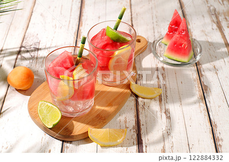Ice cold homemade lemonade or cocktail with co mint, watermelon and fruit, a recipe for a refreshing summer drink. Two glasses with fruit drink on sunny table, detox diet and weight loss concept, menu 122884332