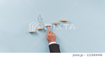 Hand of a businessman supporting wooden step for a silhouetted man to walk upwards 122884446
