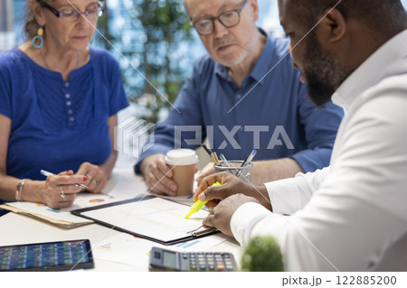 Insurance broker highlighting the important contract terms, discussing with senior couple about a new retirement plan to secure pension and finances in the future. Advisory counseling. 122885200