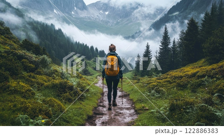 A woman is walking through a forest with a yellow backpack 122886383