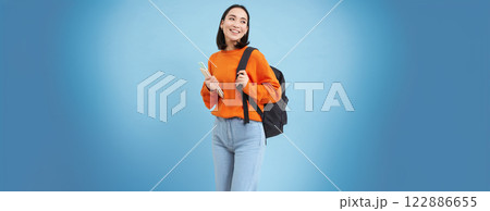 Education and students. Smiling young asian woman with backpack and notebooks, posing against blue background Education and students. Smiling young asian woman with backpack and notebooks, posing against blue background 122886655