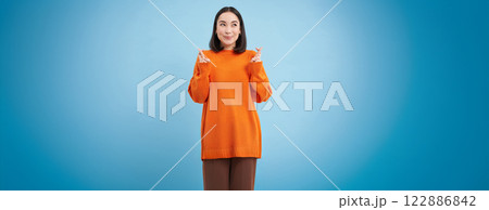 Portrait of asian woman cross fingers, hopes and prays for something, makes a wish, stands over blue background 122886842