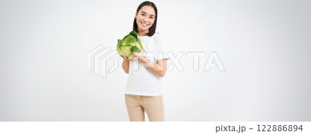 Beautiful korean woman, holding cabbage and smiling, isolated on white studio background Beautiful korean woman, holding cabbage and smiling, isolated on white studio background 122886894