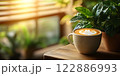Morning coffee with latte art on a wooden table next to a potted plant. Perfect for promoting a cafe or creating a relaxing atmosphere on social media. It gives a feeling of warmth start to the day. 122886993