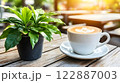 Morning coffee with latte art on a wooden table next to a potted plant. Perfect for promoting a cafe or creating a relaxing atmosphere on social media. It gives a feeling of warmth start to the day. 122887003