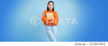 Smiling asian woman with notebooks, student with happy face, promo of college education, blue background 122887063