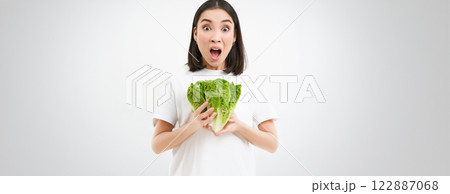 Woman with shocked face, screams, holds vegetable, raw food, eats cabbage on diet, white background Woman with shocked face, screams, holds vegetable, raw food, eats cabbage on diet, white background 122887068
