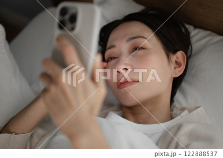 ベッドでスマホを見る女性 122888537