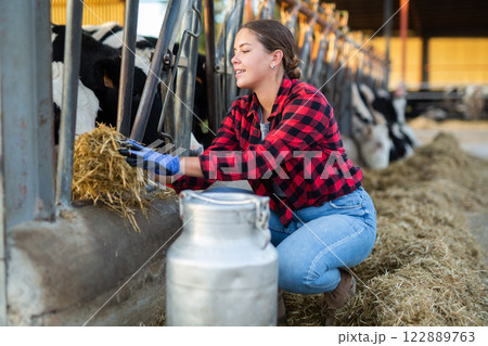 Girl feeding cows with hay in farm Girl feeding cows with hay in farm 122889763
