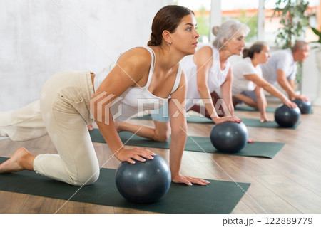 Young woman doing pilates with soft ball in studio 122889779