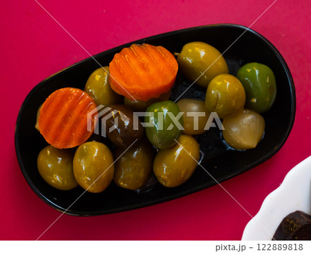 Green olives with carrot and onion on plate - typical Spanish tapas closeup 122889818